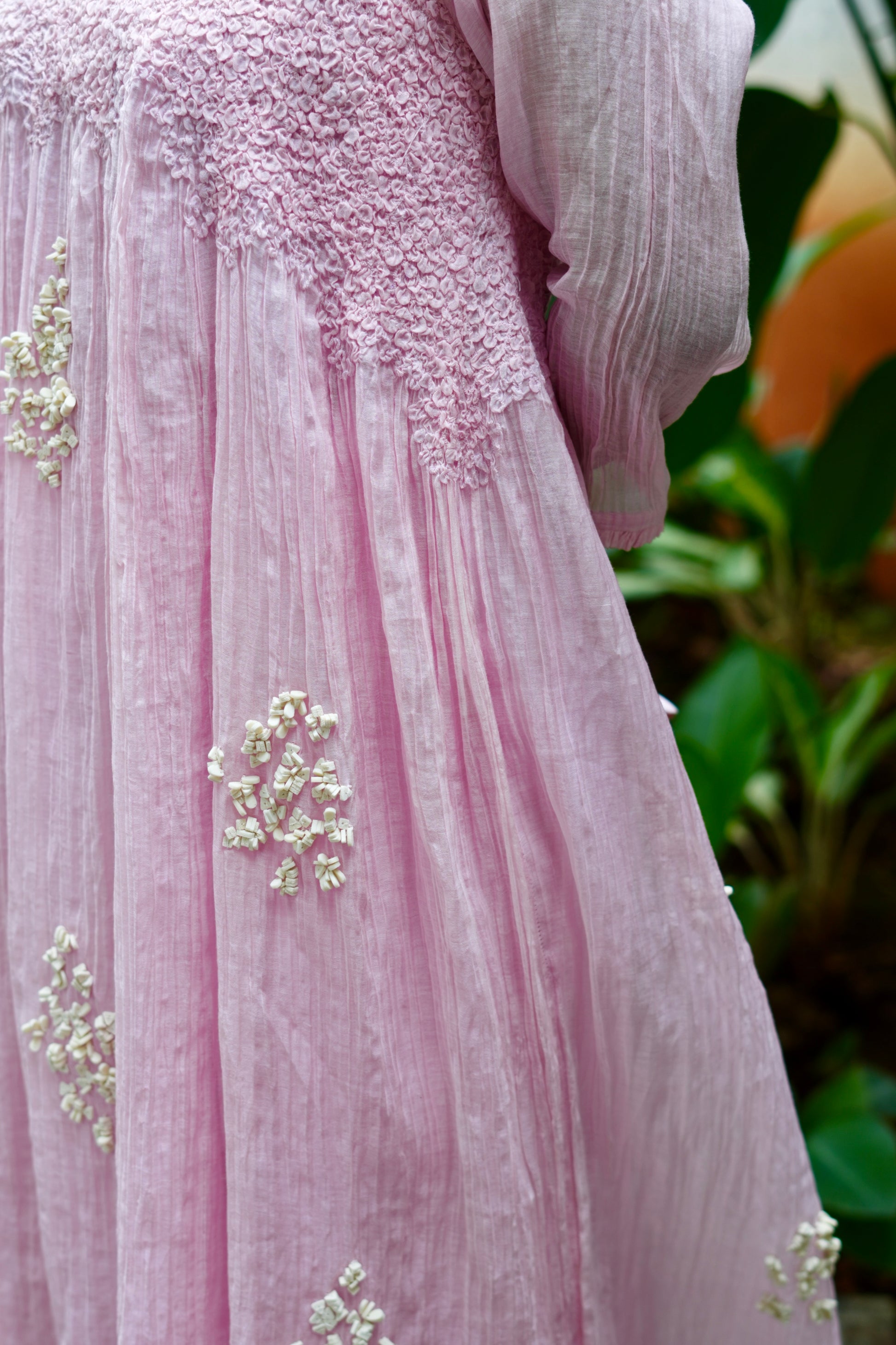Close-up of a pink embroidered dress with a blurred green background